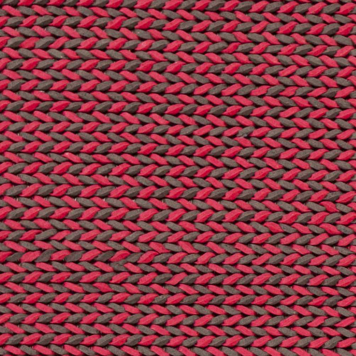 Hand-woven red and dark area rug close-up, braided crisscross weave texture