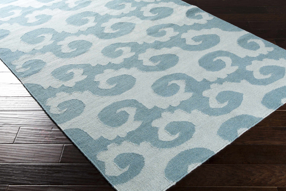 Modern hand-woven wool area rug corner with repeating blue and gray swirling pattern