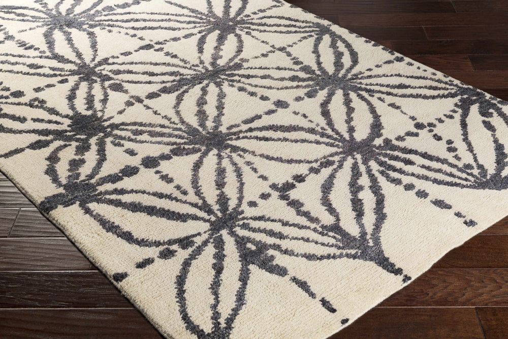 Beige and charcoal rug corner with botanical burst pattern and textured border edge