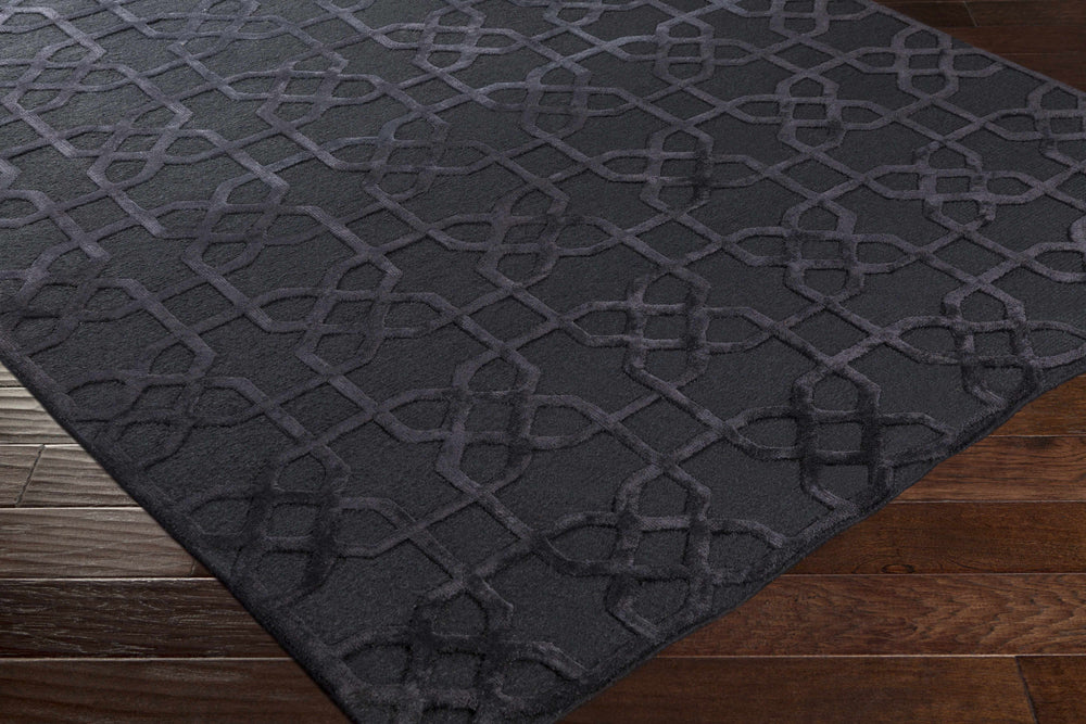 Dark wool area rug with interlocking geometric pattern, corner view