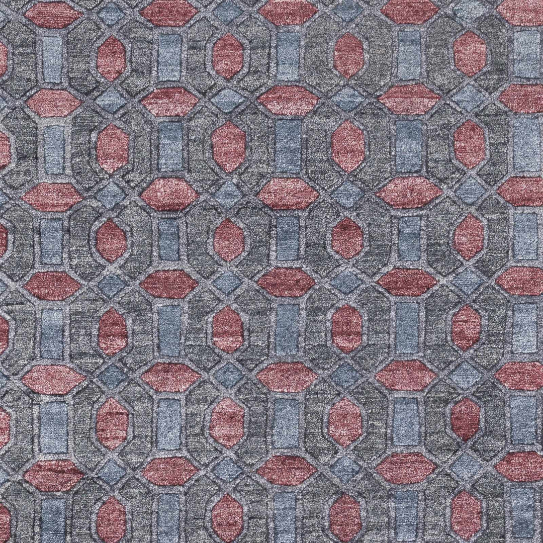 Close-up geometric hand-knotted rug pattern in gray with red and pink details
