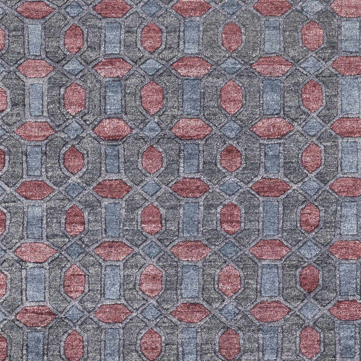 Close-up geometric hand-knotted rug pattern in gray with red and pink details