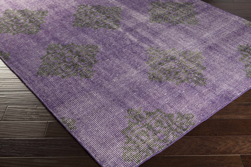 Purple area rug corner with dark medallion motifs and textured low-pile edge