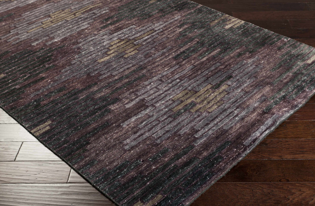 Abstract charcoal and purple area rug with low pile, angled corner edge.