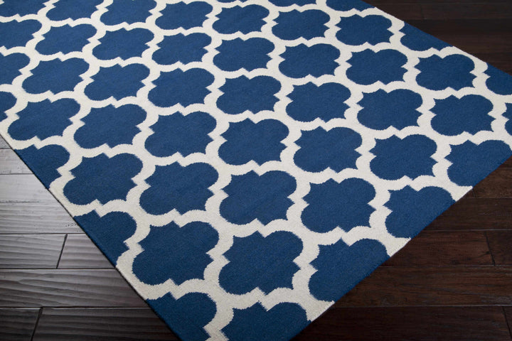 Blue and ivory geometric rug viewed at an angle on dark wood flooring