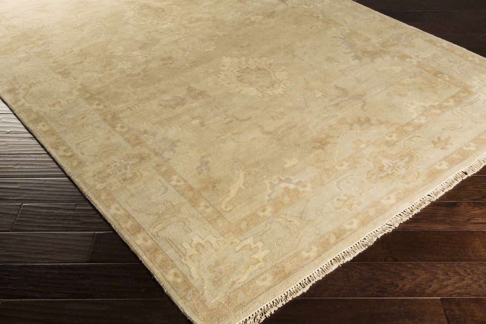 Beige Oushak rug corner showing flat woven texture and ornate vine motifs