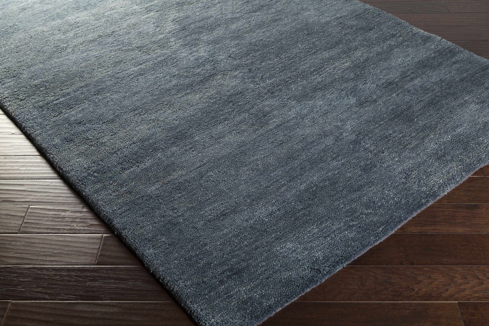 Charcoal solid hand-woven wool area rug corner with flat weave edge