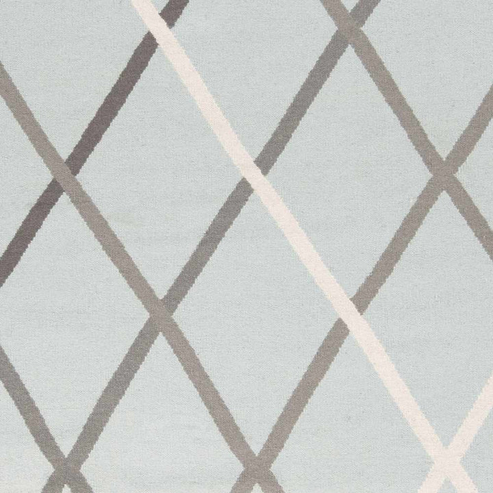 Close-up of light gray hand-woven wool rug with white and taupe diamond lattice