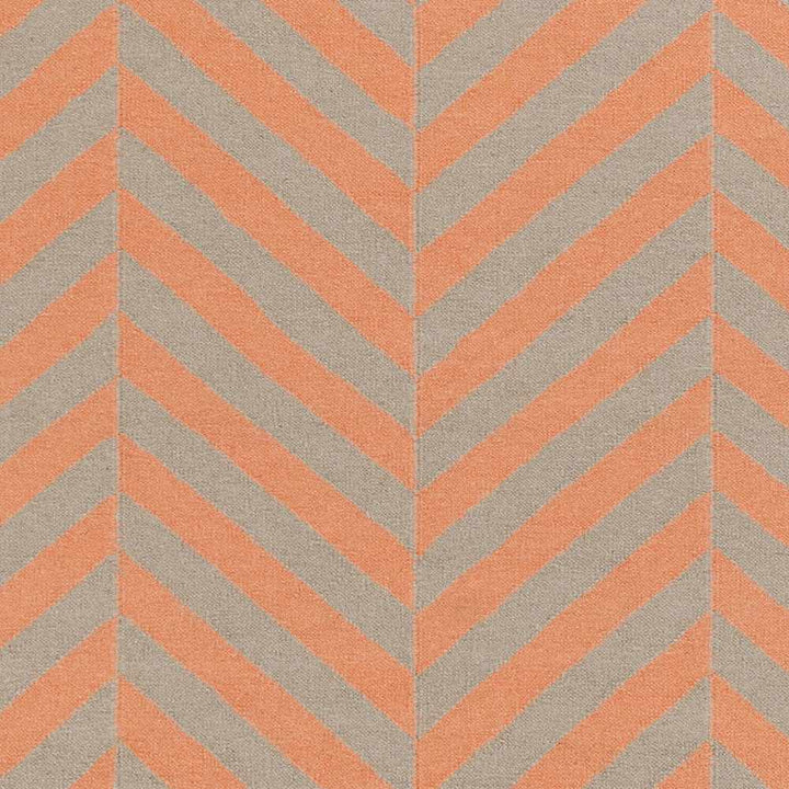 Hand-woven area rug close-up with orange chevron stripes on cream ground