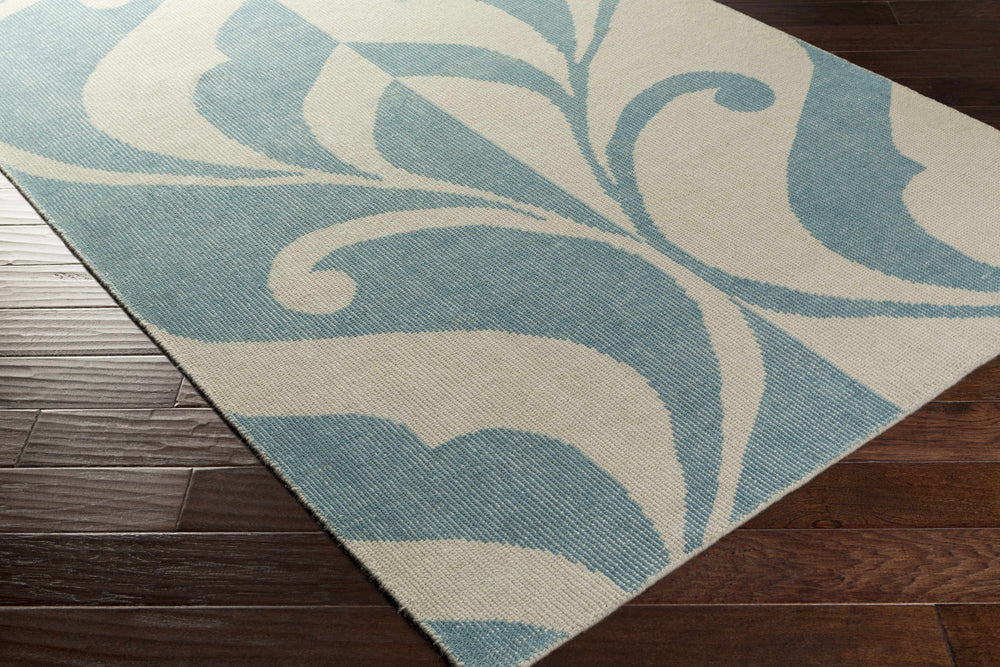 Blue and ivory hand-knotted area rug with large scroll motif, angled corner