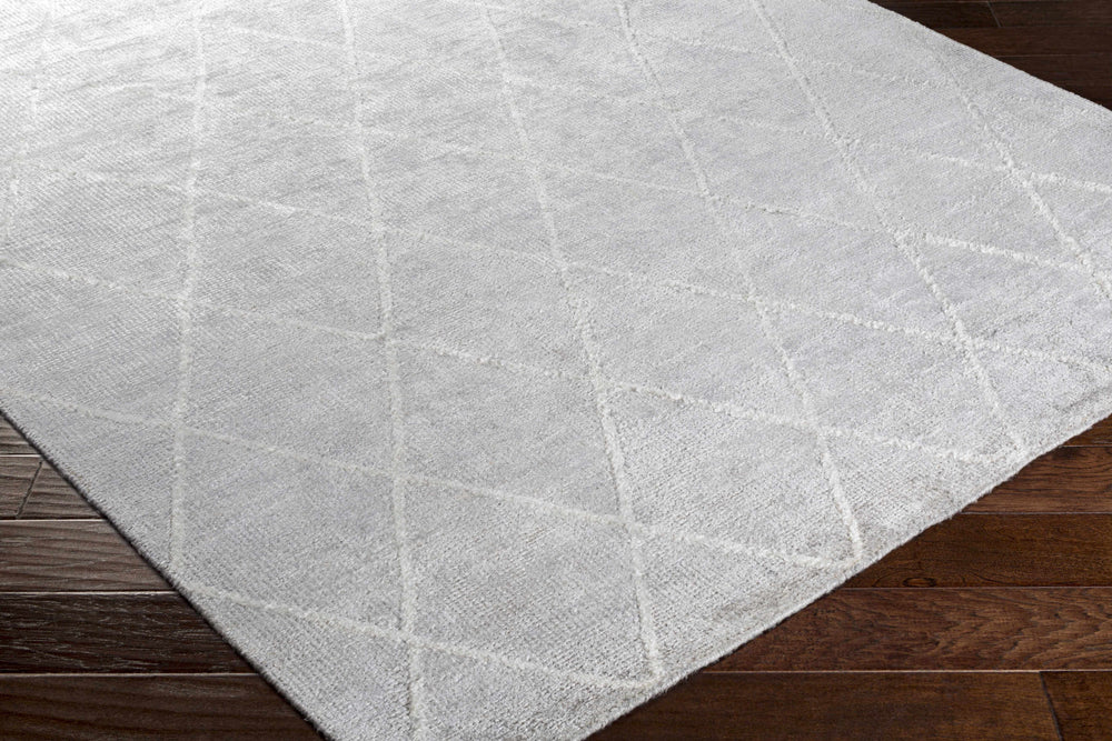 Light gray wool area rug with diamond geometric pattern and visible corner edge