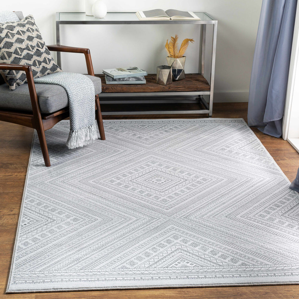 Light gray geometric area rug with diamond design, shown in a living room