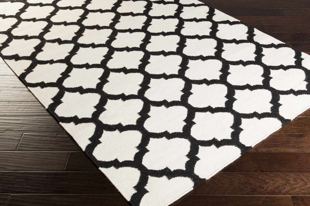 Hand-woven area rug with ivory and black trellis pattern, angled corner view