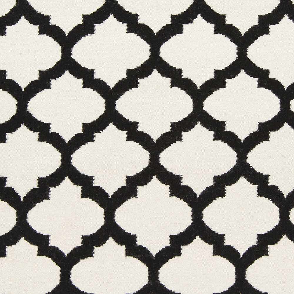 Hand-woven area rug close-up: ivory and black trellis tile pattern, high contrast
