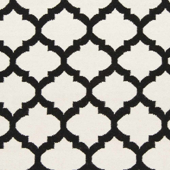 Hand-woven area rug close-up: ivory and black trellis tile pattern, high contrast