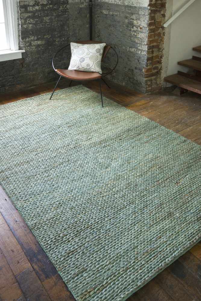 Green textured area rug laid flat in a room, visible corner and woven surface