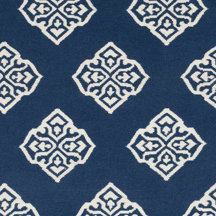 Close-up of blue area rug with ivory diamond medallion motifs