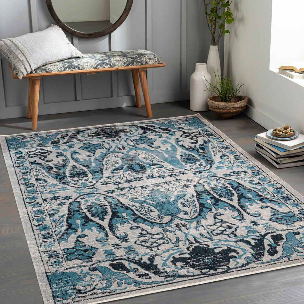 Ivory and blue ornate area rug displayed in a living room on wood flooring