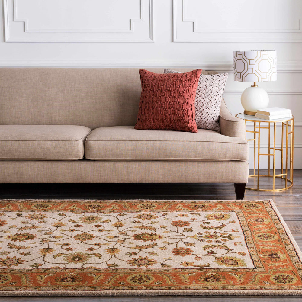 Hand-tufted wool area rug in ivory with rust border and detailed traditional floral motifs