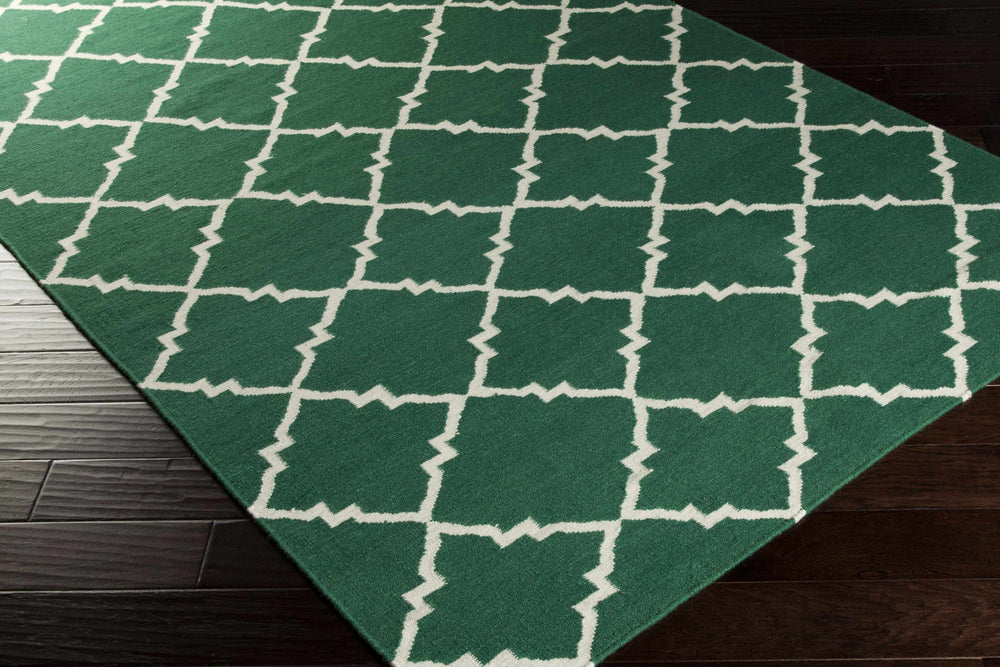 Hand-woven green area rug corner with white quatrefoil lattice geometric pattern