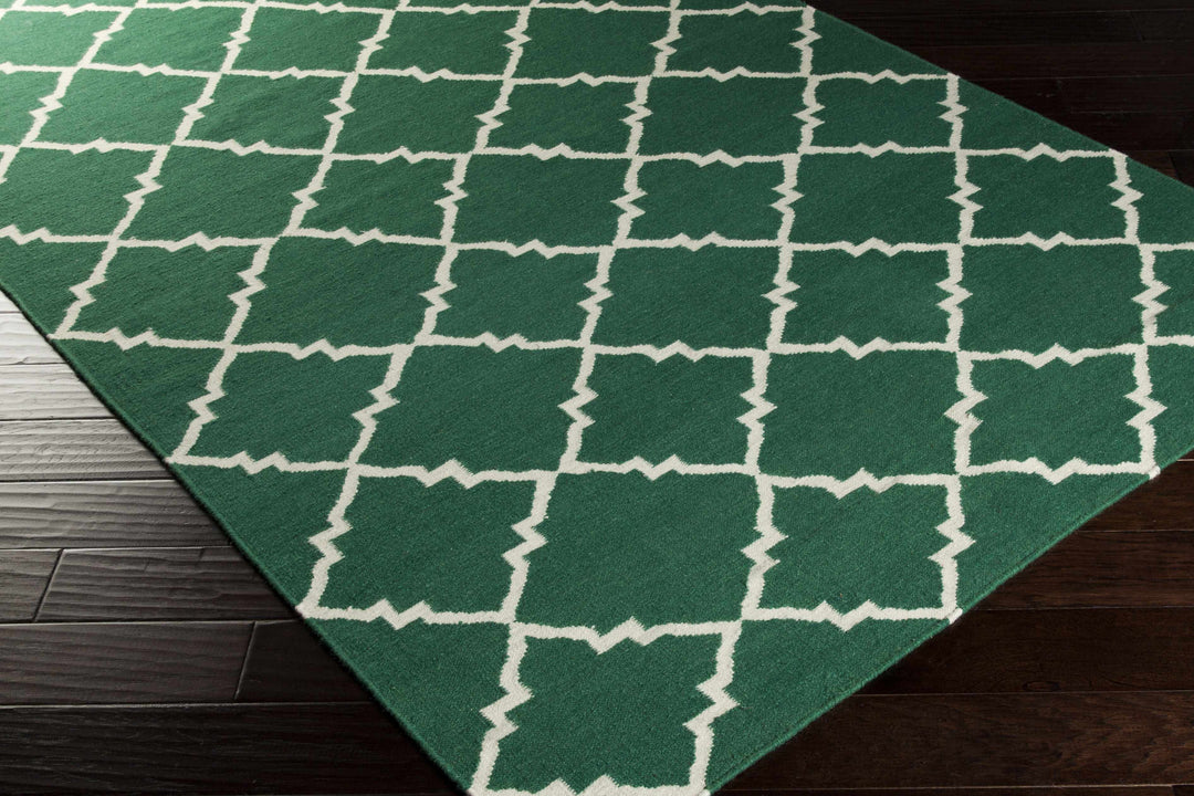 Hand-woven green area rug corner with white quatrefoil lattice geometric pattern