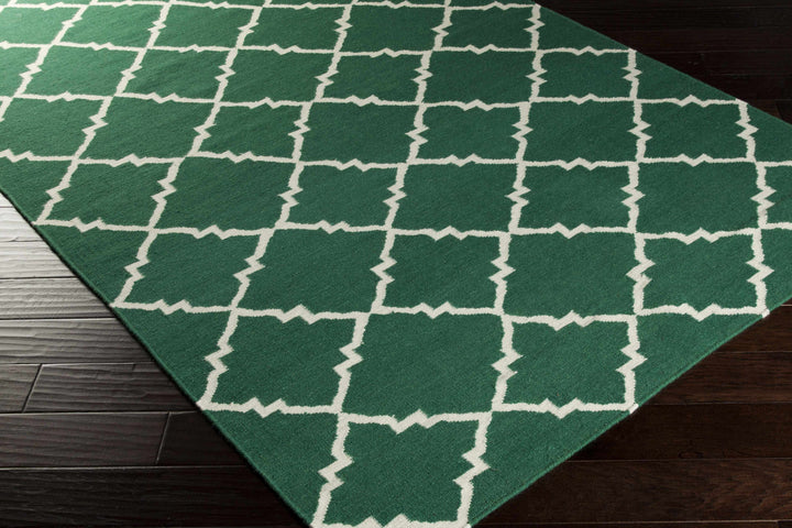 Hand-woven green area rug corner with white quatrefoil lattice geometric pattern
