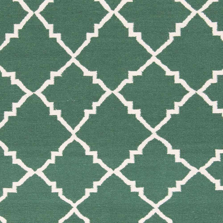 Hand-woven green area rug close-up of white geometric lattice pattern
