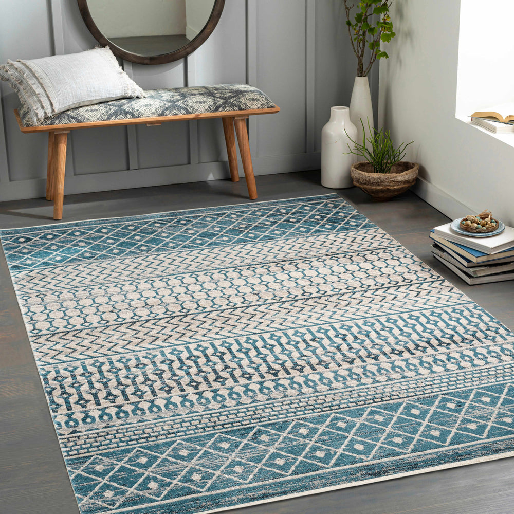 Blue geometric area rug shown in a room with visible border and zigzag motifs