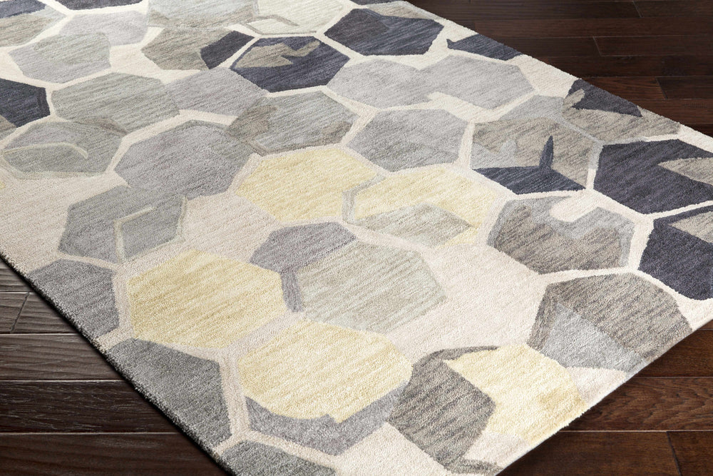 Geometric area rug with raised-look hexagon motif in gray, cream, and navy with yellow spots.