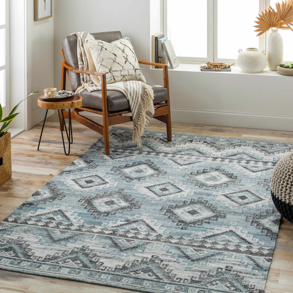 Modern geometric area rug in ivory and blue with diamond motif and border trim.