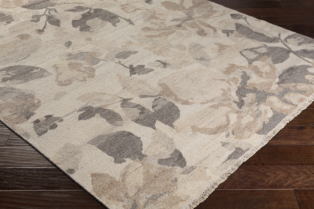 Beige wool rug corner with gray-brown leaf floral pattern and thin fringe border