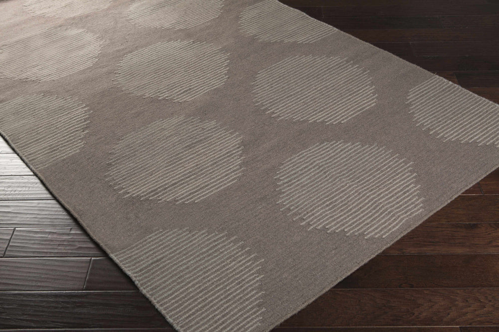 Gray wool area rug with repeating circular geometric pattern, shown from an angle.