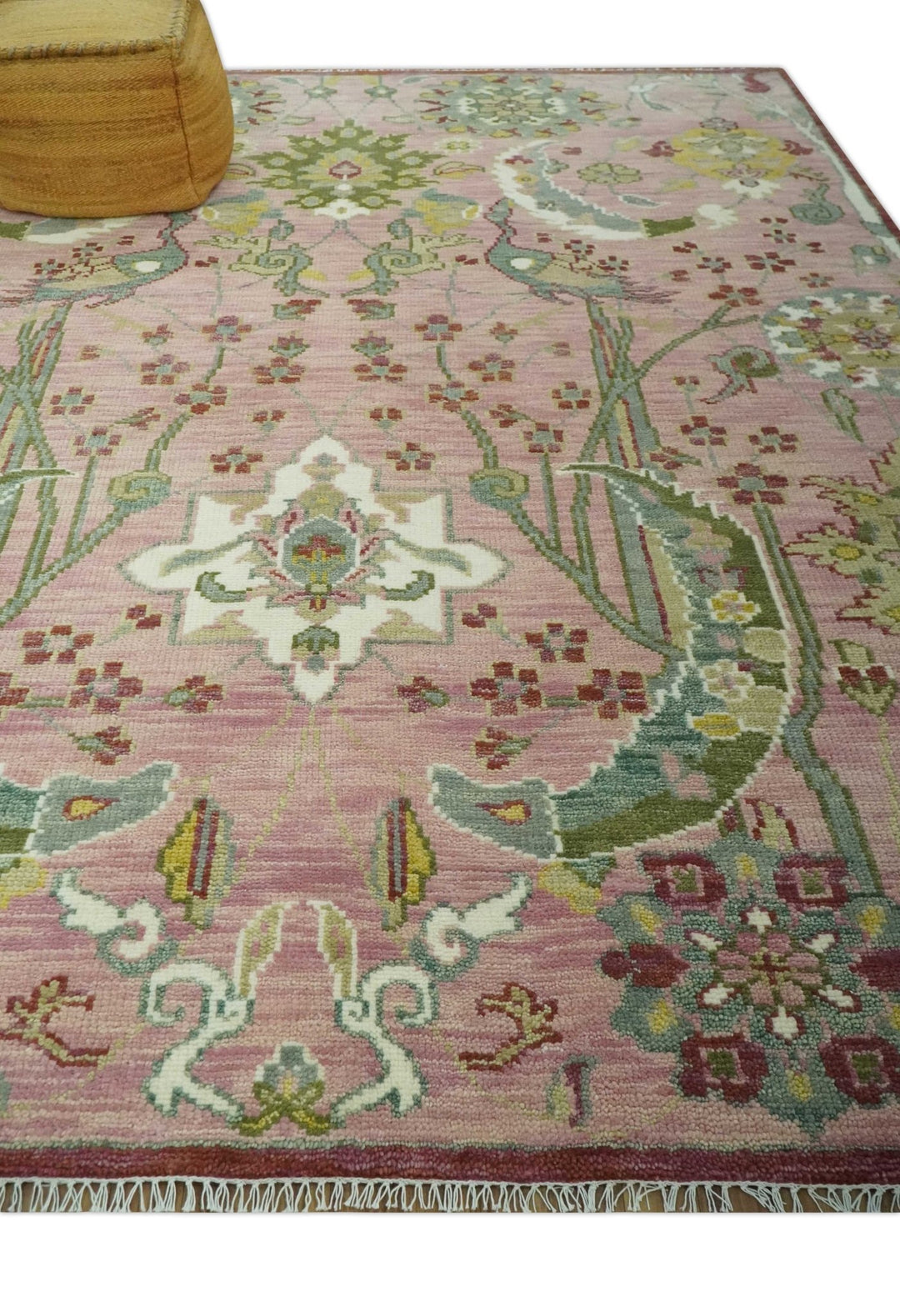 Pink and green hand-knotted wool rug with floral sprays and central emblem