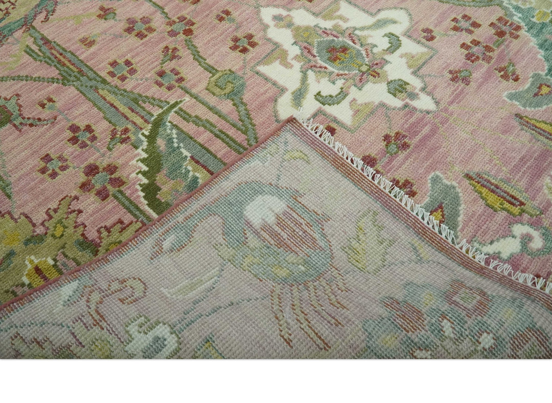 Close-up of hand-knotted wool rug border with pink, green, and cream details