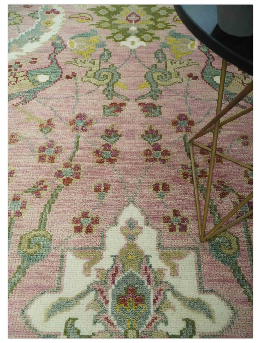 Pink and green hand-knotted wool rug with repeating lattice and floral elements