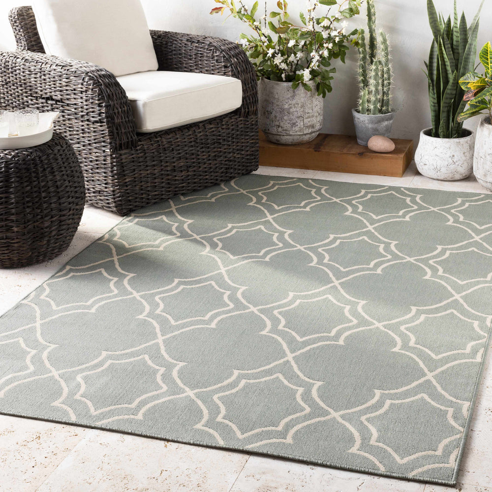 Geometric green area rug with beige lattice quatrefoil pattern on the floor