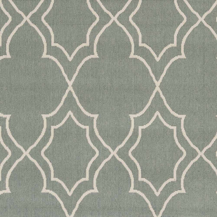 Close-up of green area rug texture with beige trellis quatrefoil geometric pattern
