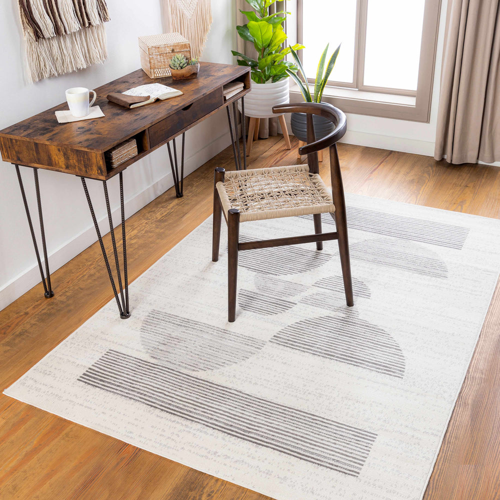 Ivory and gray abstract area rug laid flat under a chair and table